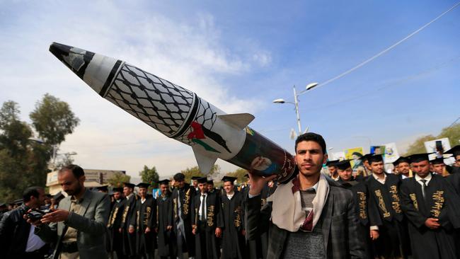 A Yemeni protester holds a mock rocket adorned with the Palestinian flag and chequerred keffiyeh along with a portrait of the late secretary general of Lebanon's Hezbollah group, Hassan Nasrallah.