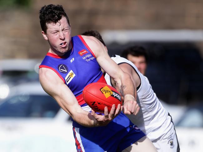 Tim Walsh of Gisborne handballs as he is tackled during the Bendigo Football League match between Gisborne and Maryborough in Gisborne on Saturday 27th April, 2013.