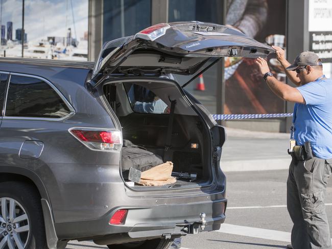 Police open the back door of a car in Docklands. Picture: Jason Edwards