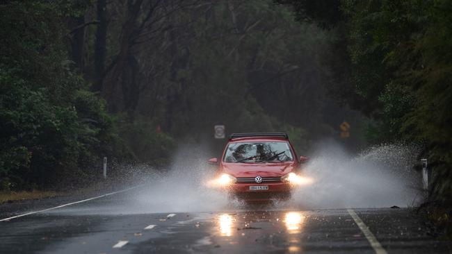 A car battles through water over Wakehurst Parkway before the road was closed due to flooding. Picture: Julian Andrews