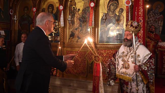 Prime Minister Scott Morrison lights his candle from Archbishop Makarios at the Greek Orthodox Easter service. Picture: AAP