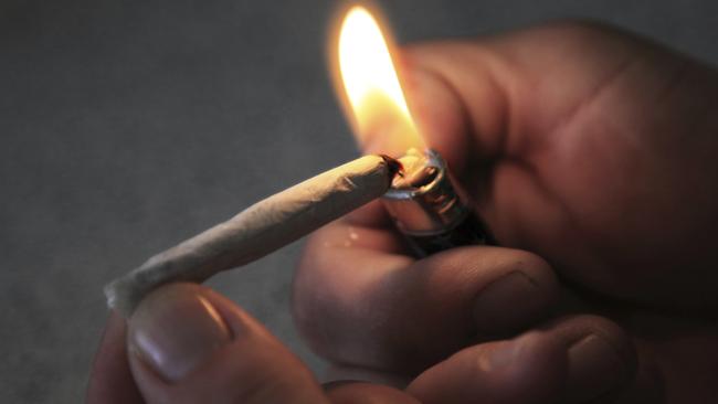 A man lights what is presumably a Marijuana cigarette in a dark environment. Better known as pot or a joint, this drug goes by many names. In actuality this is a hand-rolled tobacco cigarette, no actual drugs were used in this photo. Shot using ambient light from the lighter. Shallow depth of field, focus is on tip of cigarette and flame. Canon 5D Mark II, 24-105L lens.