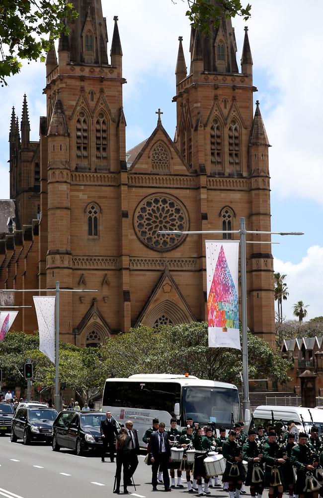 A procession including a bagpipe band walk the hearse down College St. Picture: Toby Zerna