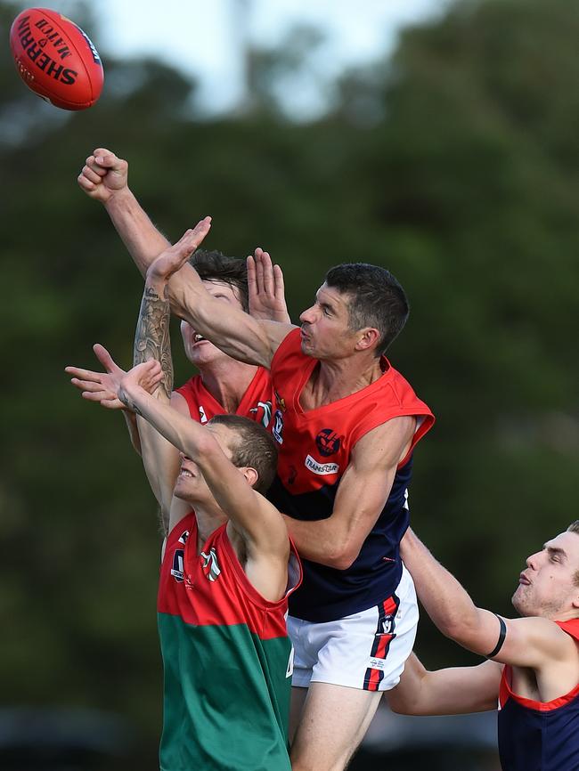 Mt Eliza’s Jim Clayton punches the ball clear of the leaping pack. Picture: Jason Sammon