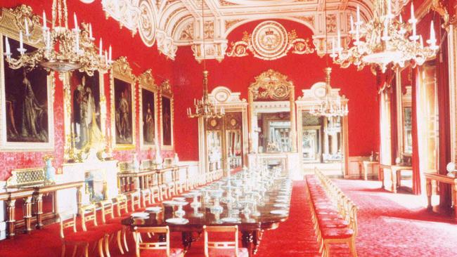 The lushly-furnished state dining room at Buckingham Palace. The decor is ‘too red’ for the King’s taste, according to one royal biographer. Picture: News Corp l