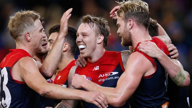 A smiling James Harmes is swamped by Melbourne teammates Bernie Vince, left, and Jack Watts during their hard-fought round 12 victory over Collingwood at the MCG. Picture: GETTY IMAGES