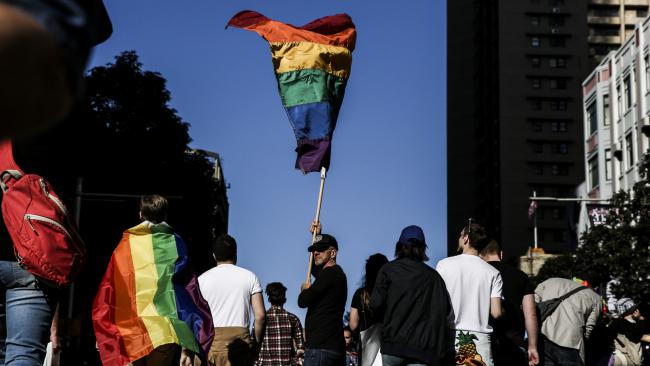 Christopher Lewis, of Surry Hills, walks down Park Street, Sydney, baring a giant rainbow flag in support of same-sex marriage. Picture: Dylan Robinson