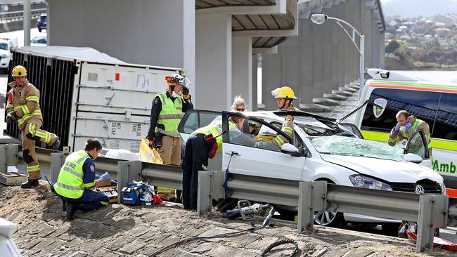 Emergency workers work to remove the person trapped in the car the container crushed after coming off a truck on the Tasman Bridge. Picture: SAM ROSEWARNE.