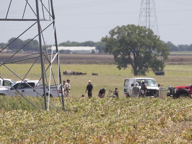 Investigators surround the scene in a field near Lockhart, Texas where a hot air balloon carrying at least 16 people collided with power lines Saturday, July 30, 2016, causing what authorities described as a "significant loss of life." (Ralph Barrera/Austin American-Statesman via AP)