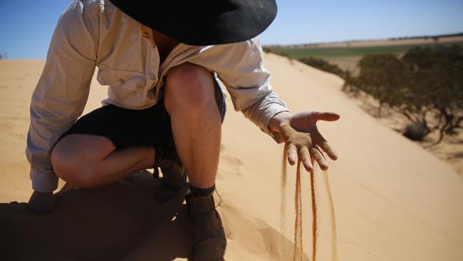 Zac Symes on his property which is slowly being covered in drifting sand dunes, in Merrinee. Picture: Alex Coppel.