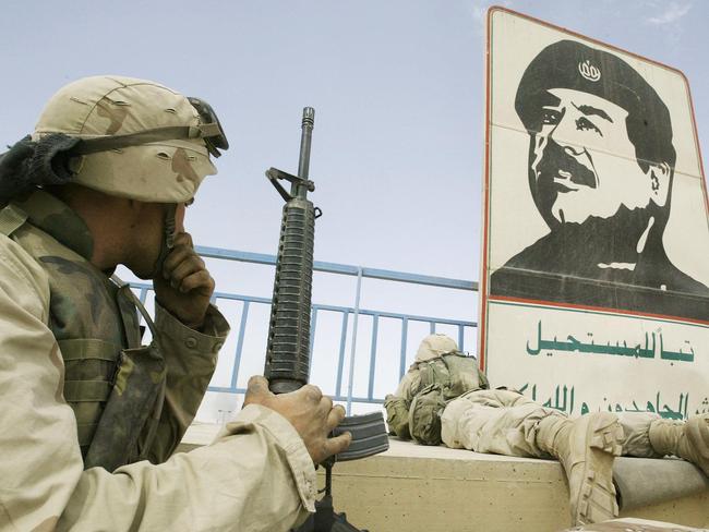 EDITORS NOTE: Graphic content / (FILES) In this file photo dated on April 10, 2003 US marines take position near a portrait of late Iraqi dictator Saddam Hussein in a stadium in Baghdad. - Twenty years after the US-led invasion of Iraq toppled Saddam Hussein, the oil-rich country remains deeply scarred by the conflict and, while closer to the United States, far from the liberal democracy Washington had envisioned. (Photo by CHRISTOPHE SIMON / AFP)