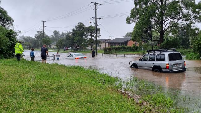 A four-wheel drive tows a sedan which became stranded in floodwater on Bray Street, Coffs Harbour, on Monday, February 28. Picture: Steve Zaal