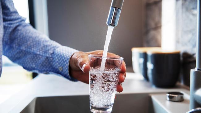 Mature male hand pouring a glass of water from tap in the kitchen sink