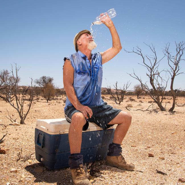 Contractor Alan Walton cools down on the dog fence outside Coober Pedy as temperatures rise above 43 degrees. Picture: Brad Fleet