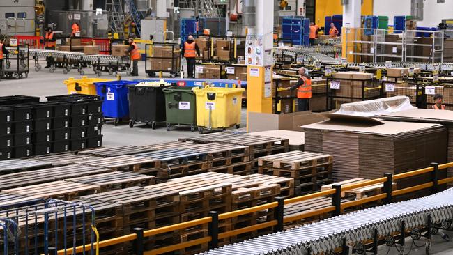 Workers move packages between conveyor belts and carts at a packing station of a redistribution centre of US online retail giant Amazon in Werne in western Germany. Picture: Ina Fassbender/AFP