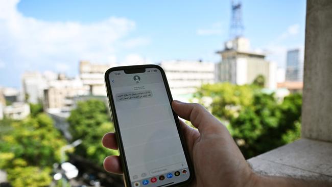 A Lebanese man checks a message received on his mobile phone in Beirut calling on people to evacuate but bombing the area right after. Picture: AFP