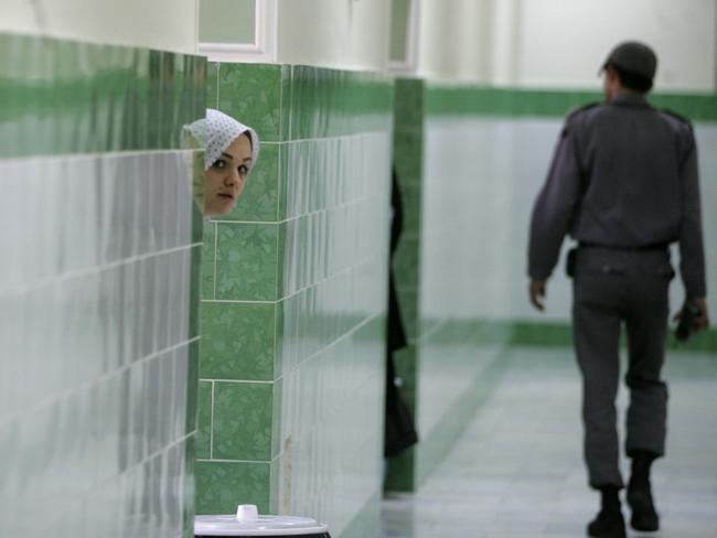 TO GO WITH AFP STORY IRAN-JUSTICE-PRISON-SOCIT BY PIERRE CELERIER  An Iranian inmate peers from behind a wall as a guard walks by at the female section of the infamous Evin jail, north of Tehran, 13 June 2006. AFP PHOTO/ATTA KENARE (Photo by ATTA KENARE / AFP)