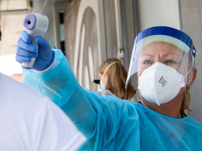 TOPSHOT - A health worker takes a patient's temperature before sending them to a tent to be tested at a COVID-19 testing site at St. John's Well Child and Family Center, amid the novel coronavirus pandemic, July 24, 2020, in Los Angeles, California. - The coronavirus pandemic hit grim new milestones July 23, with cases topping four million in the United States and three million in Europe as fresh spikes from Belgium to Tokyo to Melbourne forced new restrictions on citizens. (Photo by VALERIE MACON / AFP)