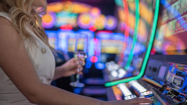 beautiful girl drinking wine alone at casino poker machine pokies istock generic