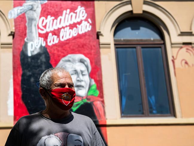 A man wearing a mask with the colours of Rome's soccer club AS Roma stands by a mural of late Italian anti-fascist and syndicalist Tina Costa, in the San Lorenzo district of Rome. Picture: AFP