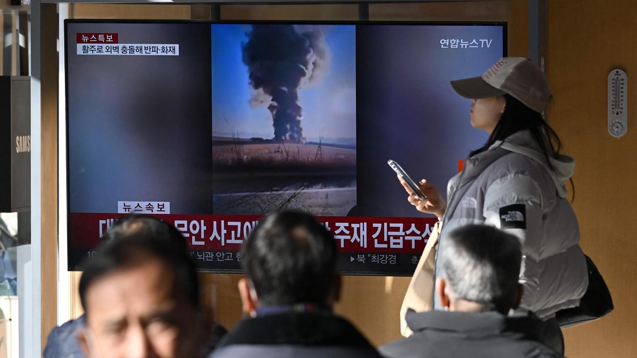 People watch a television screen broadcasting footage of an aeroplane crash at Muan international airport, at a train station in Seoul on December 29. Picture: AFP