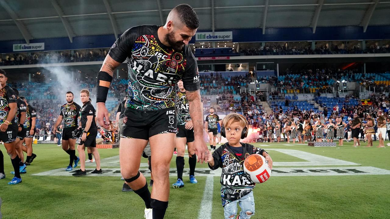 Quaden leads the Indigenous All Stars on to the field with captain Joel Thompson in February. Picture: Dave Hunt