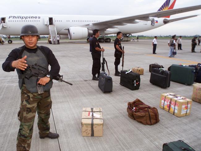 A special operations security officer at Manila Airport waves people away from a Philippines Airlines plane on which there was an attempted hijacking in May 2000.