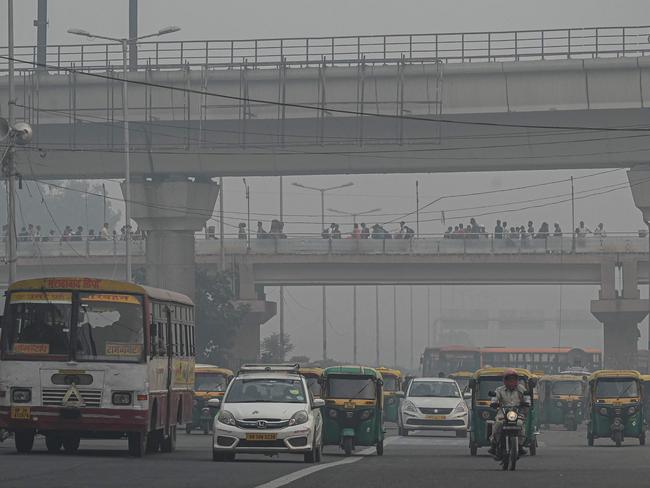 (FILES) In this file photo taken on November 5, 2021, commuters make their way along a street amid smoggy conditions in New Delhi. - Even as its capital was blanketed by toxic smog, India led the charge to weaken anti-coal pledges at the COP26 summit, with experts saying it is prioritising its economic growth over the planet's future. (Photo by Prakash SINGH / AFP) / TO GO WITH India-Environment-climate-coal,FOCUS by Abhaya SRIVASTAVA