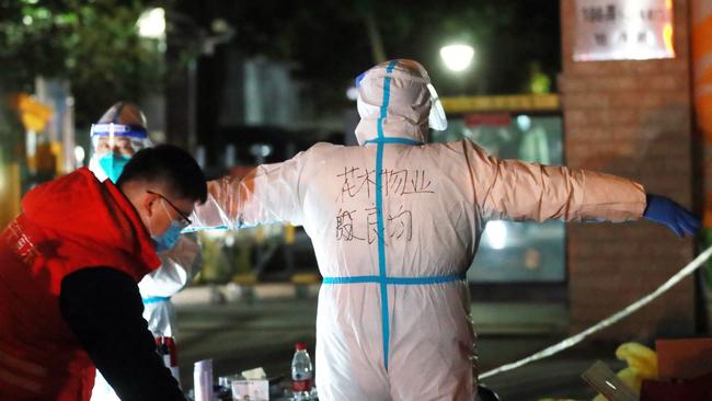 A staff member spraying disinfectant on his colleague in personal protective equipmentin in an area restricted due to the spread of Covid-19 in China. Picture: AFP.