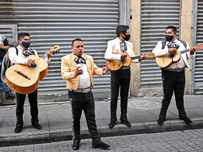 Mariachi wear face masks as they perform on the street to ask for money for the lack of work in Mexico City on August 7, 2020, amid the COVID-19 novel coronavirus pandemic. - Latin America and the Caribbean surpassed Europe on Friday to become the region hardest-hit by coronavirus deaths. Worldwide there have been more than 715,000 deaths from the virus first reported in China at the end of last year. (Photo by Pedro PARDO / AFP)