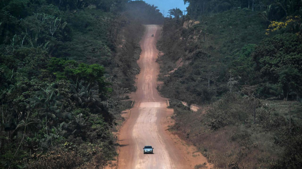 A car drives along a section under construction of the Trans-Amazonian highway (BR230) near Ruropolis. (Photo by Nelson Almeida / AFP)