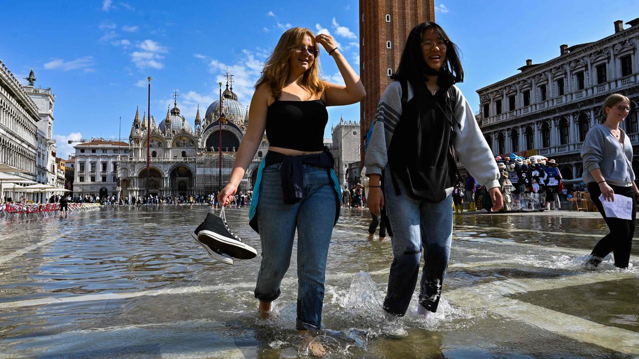 Some can be seen wearing their shows while others appear to have taken theirs off, wading through the water barefoot. Picture: Andrea Pattaro/AFP