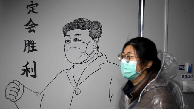 A woman wearing a face mask walks in front of a drawing of Chinese President Xi Jinping on a wall at the Leishenshan Hospital that had offered beds for coronavirus patients in Wuhan, in China’s central Hubei province on April 11, 2020. Picture: Noel Celis/AFP)