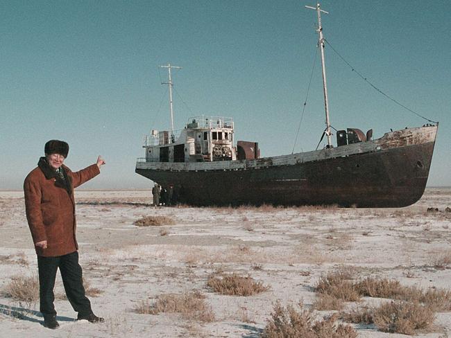 Aralsk's Mayor Alashbai Baimyrzayev points at a fishing boat on dry land, near the city of Kyzmet in Aral Sea.