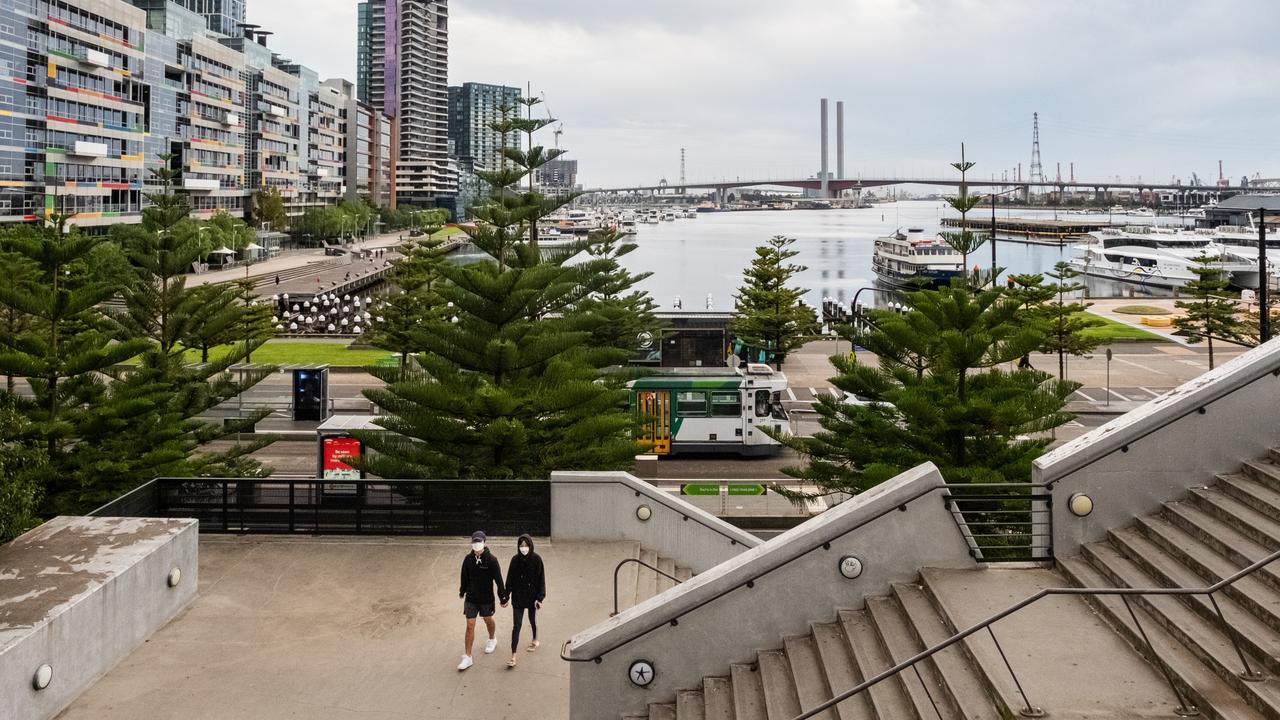 A couple wearing face masks about to walk up stairs in a quiet Melbourne Docklands precinct in 2020. Picture: Asanka Ratnayake/Getty Images