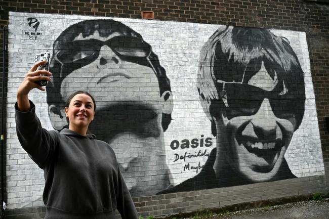 Oasis fans in front of a mural created by the Manchester-based street artist Pic.One.Art. at Sifters Records in Manchester