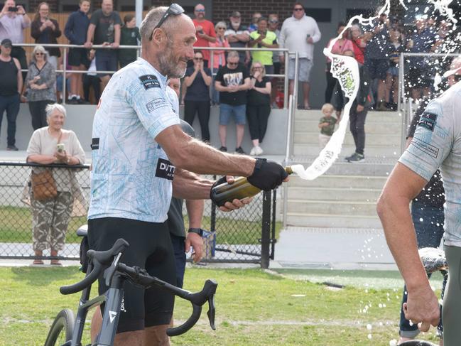 Plugger sprays his fellow riders with champagne at the end of their epic journey. Picture: Tony Gough