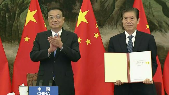 China’s Premier Li Keqiang, left, clapping as Chinese Minister of Commerce Zhong Shan holds up the agreement during the signing ceremony for the Regional Comprehensive Economic Partnership (RCEP) trade pact at the ASEAN summit in 2020. Picture: AFP/Vietnam host broadcaster