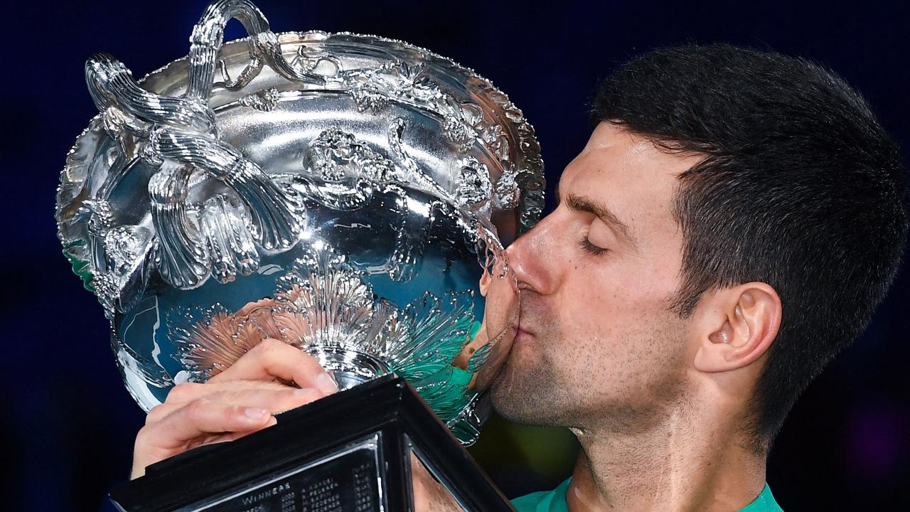 (FILES) This file photo taken on February 21, 2021 shows Serbia's Novak Djokovic kissing the Norman Brookes Challenge Cup trophy following his victory against Russia's Daniil Medvedev in the men's singles final on day 14 of the Australian Open tennis tournament in Melbourne. - Novak Djokovic was listed for a night match on January 17, 2022 to open his Australian Open title defence, as he awaited a court decision on his appeal against deportation. (Photo by William WEST / AFP) / TO GO WITH AFP STORY Tennis-AUS-Open-men-five -- IMAGE RESTRICTED TO EDITORIAL USE - STRICTLY NO COMMERCIAL USE --