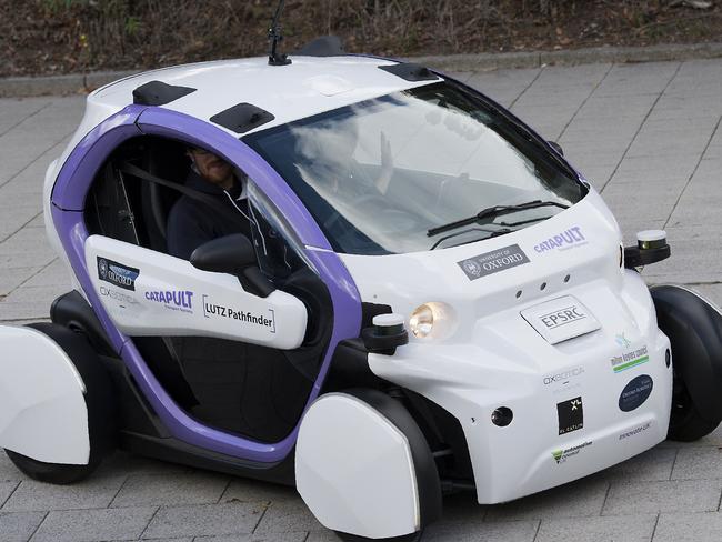 People look towards an autonomous self-driving vehicle, as it is tested in a pedestrianised zone, during a media event in Milton Keynes, north of London, on October 11, 2016. Driverless vehicles carrying passengers took to Britain's streets for the first time on Tuesday in a landmark trial which could pave the way for their introduction across the country. The compact two-seater cars trundled along a pedestrianised zone in Milton Keynes, north of London, in a trial by Transport Systems Catapult (TSC) which plans to roll out 40 vehicles in the city. / AFP PHOTO / JUSTIN TALLIS