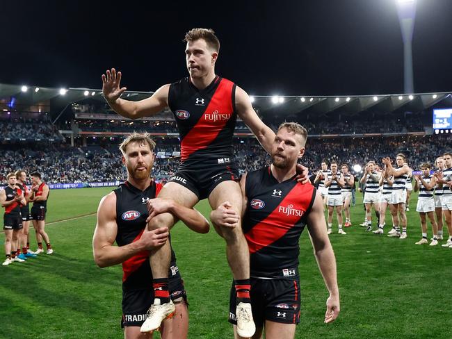 GEELONG, AUSTRALIA - JULY 15: Zach Merrett of the Bombers is chaired from the field after his 200th match by teammates Dyson Heppell (left) and Jake Stringer (right) during the 2023 AFL Round 18 match between the Geelong Cats and the Essendon Bombers at GMHBA Stadium on July 15, 2023 in Geelong, Australia. (Photo by Michael Willson/AFL Photos via Getty Images)
