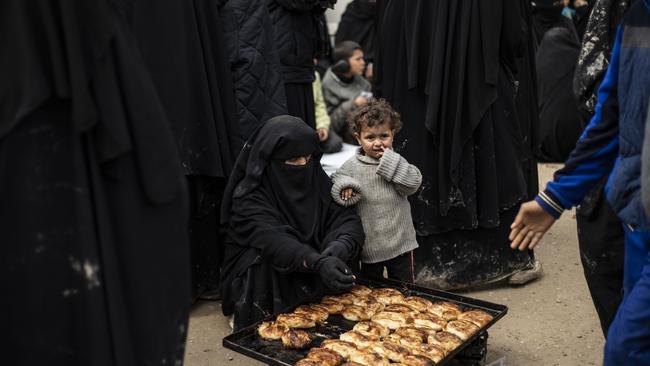 A veiled woman, living in Al-Hawl camp which houses relatives of Islamic State group members, sits next to a tray of bread in northeastern Syria. Picture: AFP