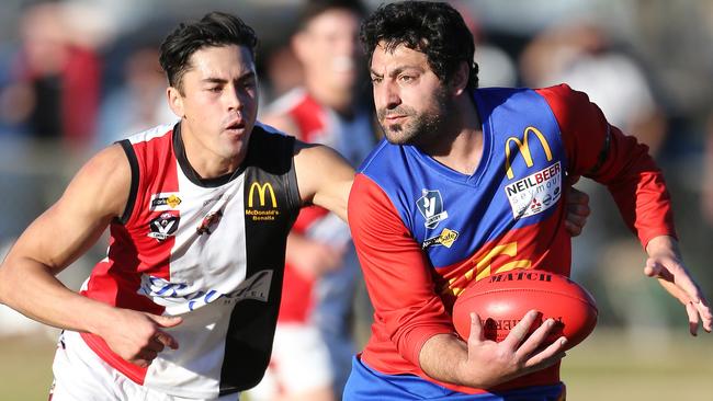 Edging out: Seymour Lion Saad Saad prepares to dispose of the ball with Benalla Saint David Mennen in hot pursuit. Pictures: Yuri Kouzmin