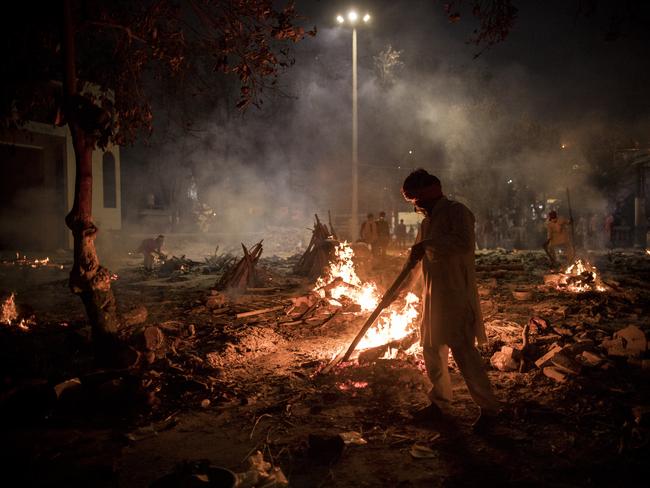 Workers at a New Delhi crematorium where multiple funeral pyres are burning for patients who lost their lives to Covid-19. Picture: Getty Images