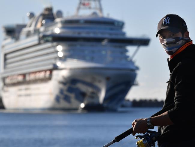 A fisherman wearing a face mask looks on as the Ruby Princess, with crew only onboard, docks at Port Kembla, Wollongong, Monday, April 6, 2020. A criminal investigation will be launched into how cruise line operator Carnival Australia was allowed to disembark Ruby Princess passengers in Sydney, resulting in several deaths and COVID-19 outbreaks throughout the country. (AAP Image/Dean Lewins) NO ARCHIVING