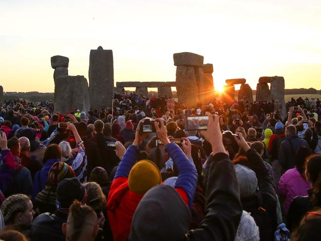 Revellers watch the sunrise as they celebrate the pagan festival of Summer Solstice at Stonehenge in Wiltshire, southern England on June 21, 2018. Picture: Geoff Caddick