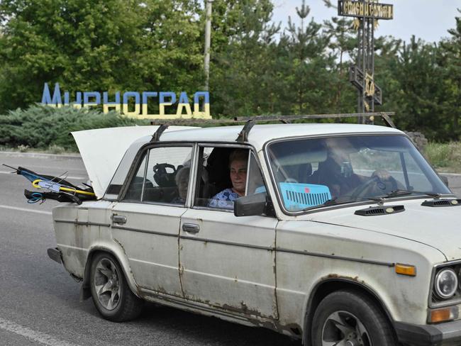 People ride in a car loaded with belongings as they leave the town of Myrnohrad after more Russian attacks. Picture: AFP