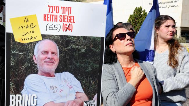 People next to a poster of Israeli hostage Keith Siegel watch on a screen at ‘hostage square’ in Tel Aviv as hostages are released. Picture: AFP