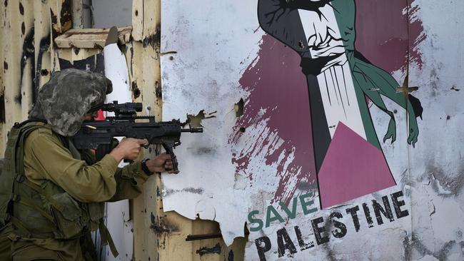 A 'save Palestine' sign adorns a wall as Israeli infantry soldiers take part in a live firing tactical advance exercise near the border in readiness for possible deployment across the border into Gaza. Picture: Christopher Furlong/Getty Images