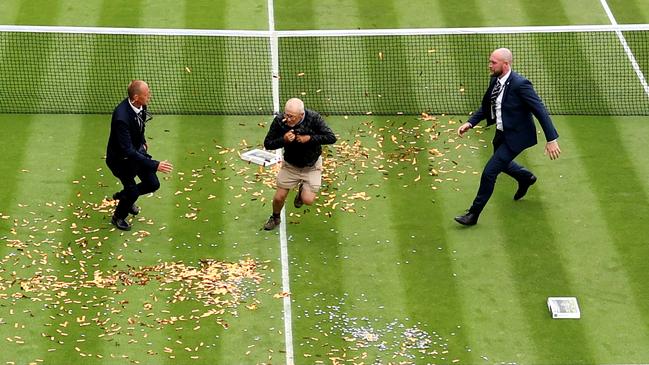 A protester scatters jigsaw puzzle pieces and orange strips of paper at Wimbledon. Picture: Getty Images